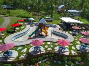 an outdoor pool with a water park with umbrellas at Balay Ni Tatay Farm Resort by Cocotel in Babatngon