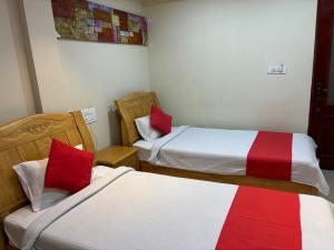 two beds in a room with red and white at STAYMAKER DV Residency in Bhadrāvati