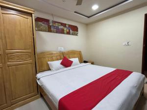 Schlafzimmer mit einem Bett mit roter und weißer Bettwäsche in der Unterkunft STAYMAKER DV Residency in Bhadrāvati