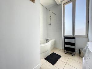 a white bathroom with a tub and a window at L'écrin des écoles in Saint-Rambert-dʼAlbon
