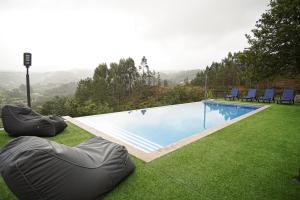 a swimming pool with two bean bags on the grass at Quinta do Além 