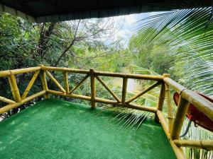 Lakefront Tree Escape in Buriram, Thailand في بوريرام: سور خشبي على شرفة مع أرضية خضراء