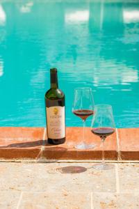 two glasses of red wine next to a swimming pool at Borgo Vescine in Radda in Chianti