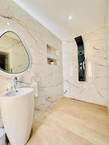 ein weißes Badezimmer mit einem Waschbecken und einem Spiegel in der Unterkunft Villa dream oujda in Oujda