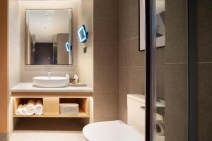 y baño con lavabo, aseo y espejo. en Rezen Longuu Hotel Guangzhou, en Guangzhou