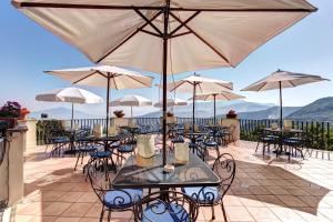 
a patio area with tables, chairs and umbrellas at Grand Hotel Hermitage in SantʼAgata sui Due Golfi
