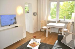 ein Wohnzimmer mit einem Sofa, einem TV und einem Tisch in der Unterkunft App 44 Seestern Ferienwohnung in Timmendorfer Strand