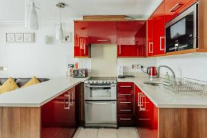 a kitchen with red cabinets and white counter tops at Lovely One Bedroom Flat in Bournemouth +3 photos