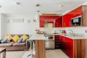 a kitchen with red cabinets and a couch at Lovely One Bedroom Flat in Bournemouth
