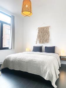- une chambre blanche avec un grand lit et des oreillers bleus dans l'établissement NYAMAN, à Ostende