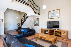 a living room with a couch and a tv at Ocean Sunsets - 2 bedroom converted warehouse apartment in Fremantle