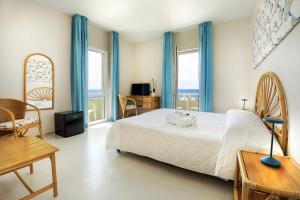 a bedroom with a large bed with blue curtains at Hotel Mida in Scoglitti