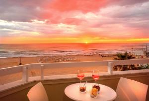 un tavolo con due bicchieri di vino e una vista sulla spiaggia di Hotel Mida a Scoglitti