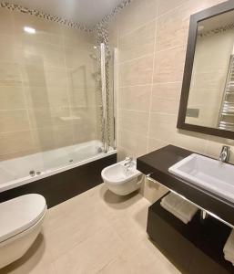 a bathroom with a toilet and a sink and a tub at Piso de lujo con piscina y gym, a 2min de la playa in A Coruña