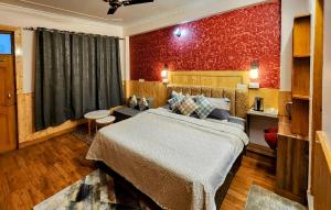 The Bougainvillea, Mcleodganj في دارامشالا: غرفة نوم بسرير كبير وجدار احمر