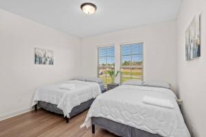 2 camas en un dormitorio con paredes blancas en Four-bedroom house in Iowa, La, en Iowa