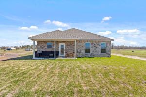 una casa con un gran patio delante de ella en Four-bedroom house in Iowa, La, en Iowa