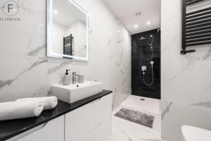 a white bathroom with a sink and a mirror at Flatbook - City Center Apartments Monte Cassino in Sopot