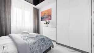 a white bedroom with a bed and a window at Flatbook - City Center Apartments Monte Cassino in Sopot