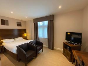 a hotel room with a bed and a flat screen tv at Cave Castle Hotel in South Cave