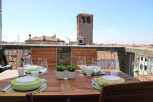 un tavolo in legno con piatti e bicchieri da vino su un balcone di Apartment with terrace in Chioggia's main square a Chioggia