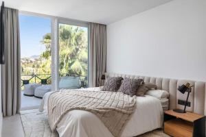 a white bedroom with a bed and a large window at Stunning 3 bedroom Apt near golf and beach! RDR350 in Benahavís +27 photos