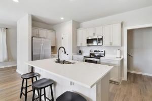 a kitchen with white cabinets and a kitchen island with stools at Brand-new home close to LSU campus in Baton Rouge