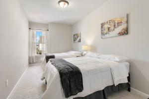 a white bedroom with two beds and a window at Brand-new home close to LSU campus in Baton Rouge
