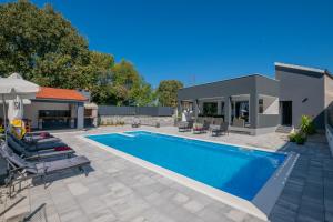 einen Pool mit Stühlen und ein Haus in der Unterkunft Villa Erwin with heated pool in Imotski