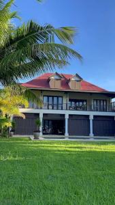 a large building with a red roof and a palm tree at Paradise Villa Eden Island in Mahe