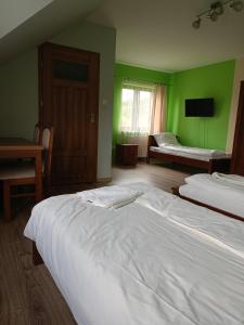 um quarto verde com duas camas e uma televisão em Gościniec Na Stoku pokoje 2,3,4 osobowe, cisza, spokój, widok na stok narciarski, lasy, łaki em Bobliwo