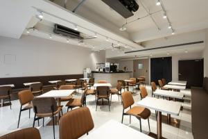 een eetkamer met tafels en stoelen en een keuken bij Autumn Willow Hotel in Taichung