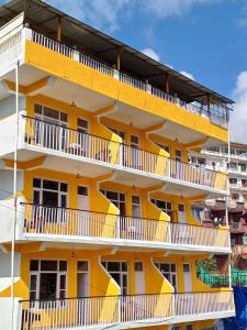 un edificio de apartamentos amarillo con balcones blancos en The Bougainvillea, Mcleodganj, en Dharamshala