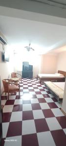 a room with a checkered floor with beds and tables at Nhật Bình 2 in Ho Chi Minh City