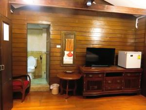 a bathroom with a toilet and a television on a wooden wall at Sira Boutique Chiang Mai in Chiang Mai