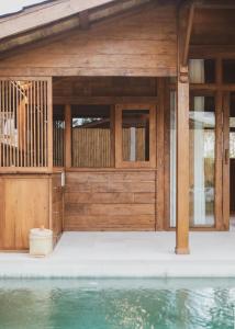 a wooden house with a pool in front of it at Kalyana Villa Gili Air in Gili Air