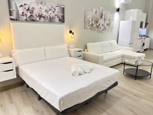 um quarto branco com uma cama e um sofá em Ribera Home em Córdoba