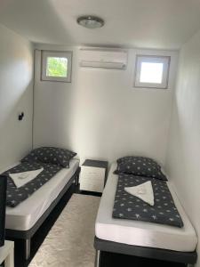 two beds in a small room with two windows at Arany Apartman in Cegléd