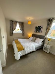 a bedroom with a large bed and two windows at Spacious Apartment in Brooklands in Milton Keynes