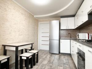  La cuisine est équipée de placards blancs et d'un réfrigérateur. dans l'établissement 0147 New flat near airport Zhulyany Sofievskaya Borshchagovka, à Kiev