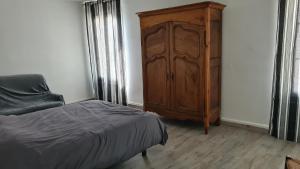 a bedroom with a wooden cabinet next to a bed at Maison Bourgueil 3 chambres in Bourgueil