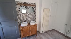uma casa de banho com 2 lavatórios e um espelho na parede em Maison Bourgueil em Bourgueil