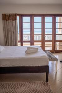 a bed with two towels on it in a room with windows at SANDS AND ROCKS APARTMENT in Mombasa