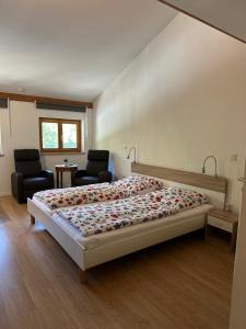 a bedroom with a bed and two chairs at Manthaler in Berg am Starnberger See