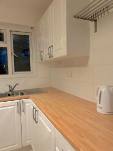 a kitchen with white cabinets and a wooden counter top at Blue Poppy in London