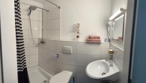 a white bathroom with a sink and a toilet at Manthaler in Berg am Starnberger See