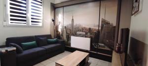 una sala de estar con sofá y una foto de la ciudad en Chez Louis - Appartement Central en Rethel