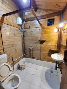 a wooden bathroom with a toilet and a sink at Pousada Donaciana - Beach Cottages in Baga