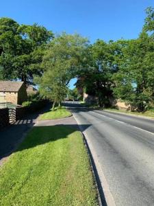 an empty road with a tree on the side of the road at Ramshill House in Cracoe