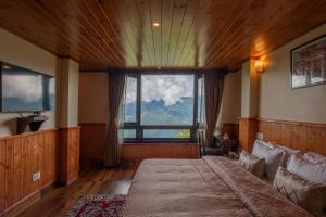 um quarto com uma cama grande e uma janela grande em StayVista's Himalayan Horizon - Mountain & Valley-View Villa with Heater em Gangtok